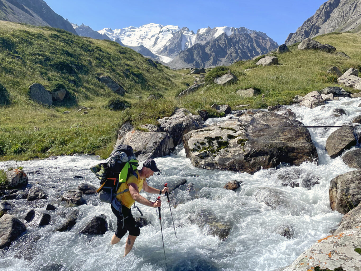 A man with a pack crossing mountain river
